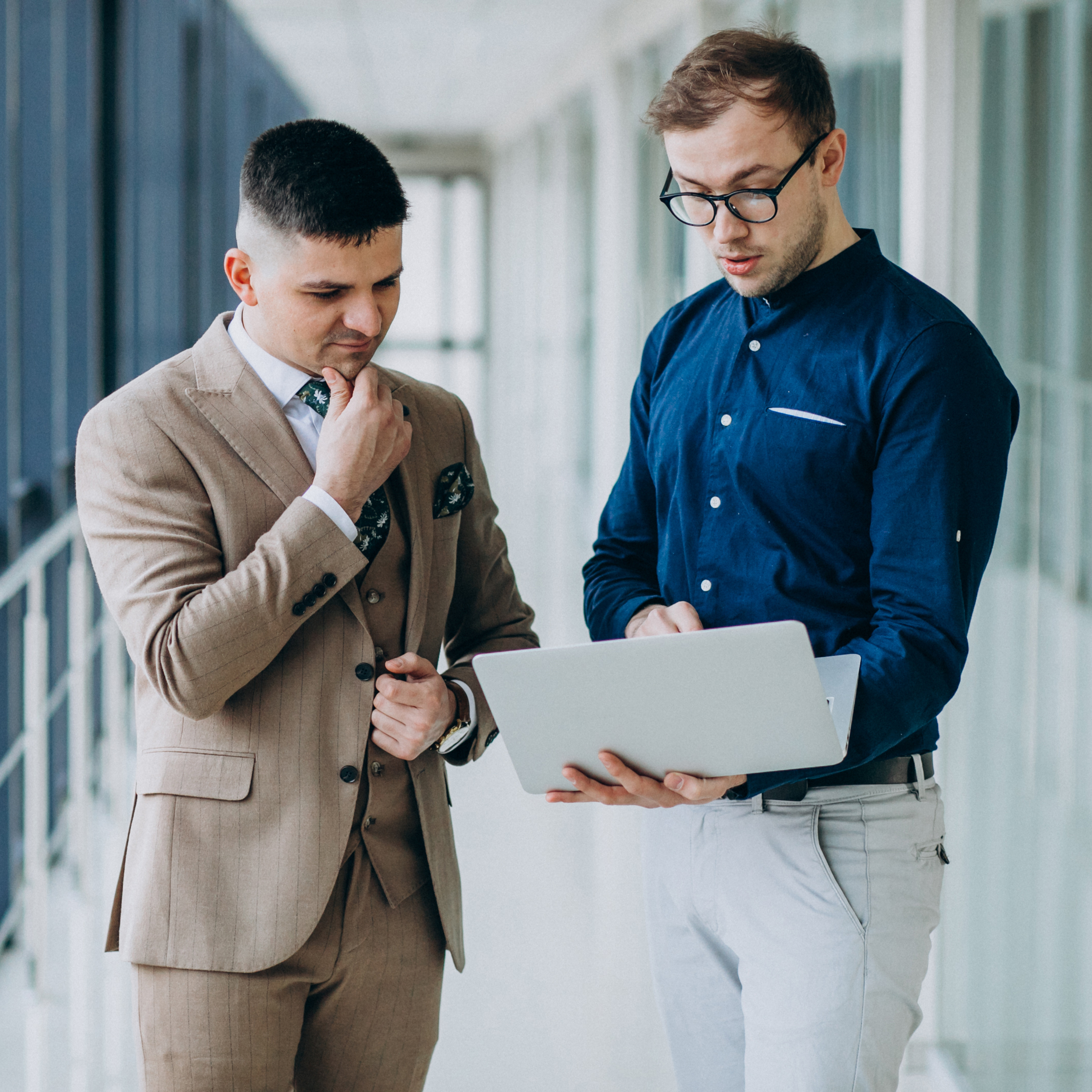 two-male-colleagues-office-standing-with-laptop